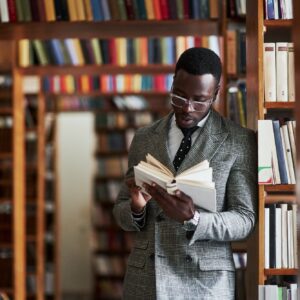 An African American man in a business suit standing in a library in the reading room